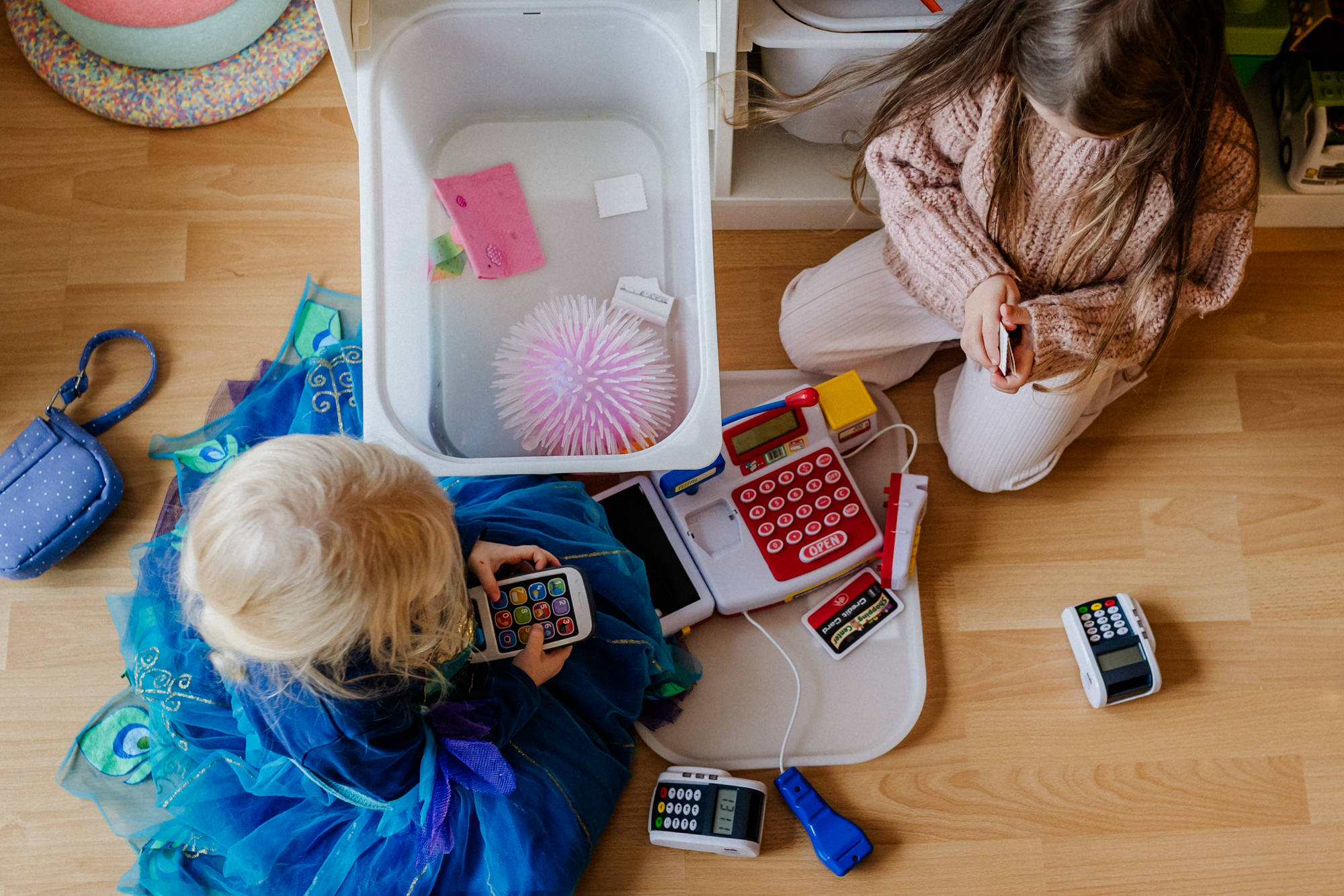 zwei Kinder, die mit Kassenrollen und Kassen spielen