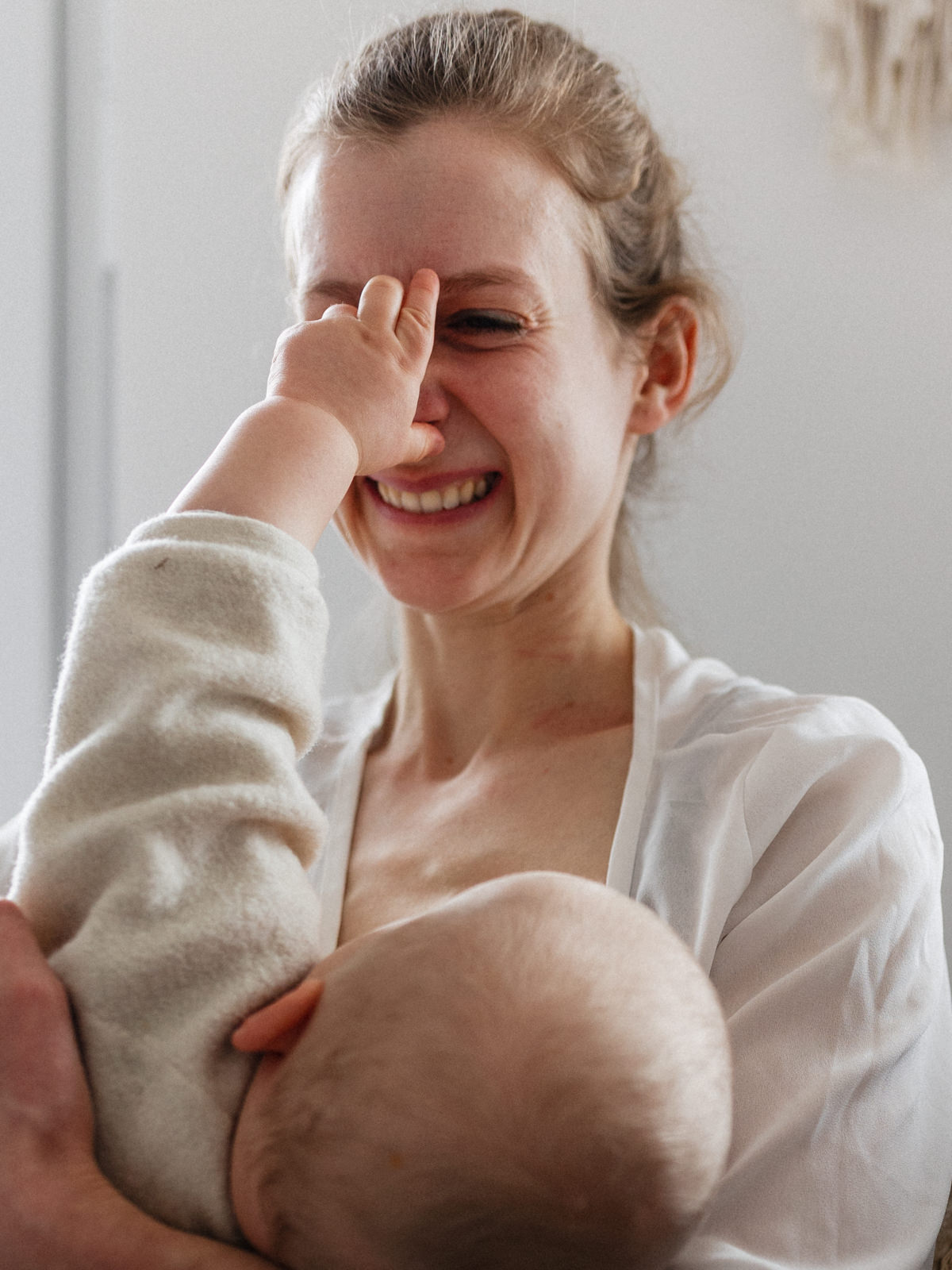 stillendes Baby, das an die Nase seiner Mutter greift